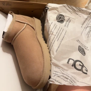 UGGs sand - Säljer ett par supermysiga beige boots från UGG i nytt skick. Perfekta för höst och vinter med sin varma och bekväma insida. De har en klassisk design utan snörning, vilket gör dem enkla att ta på och av. Passar perfekt till både vardag och avslappnade tillfällen. Färgen sand och aldrig använda 👍🏼