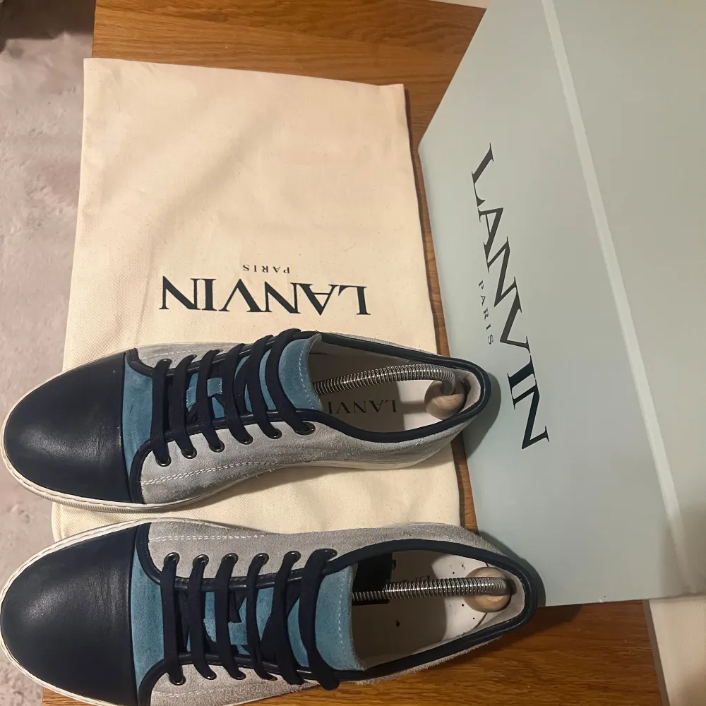 Snygga Lanvin sneakers i en mix av blått och grått. De har en stilren design med snörning och en vit sula. Perfekta för både vardag och festliga tillfällen. Skorna kommer i originalförpackning med dustbag.. Skor.