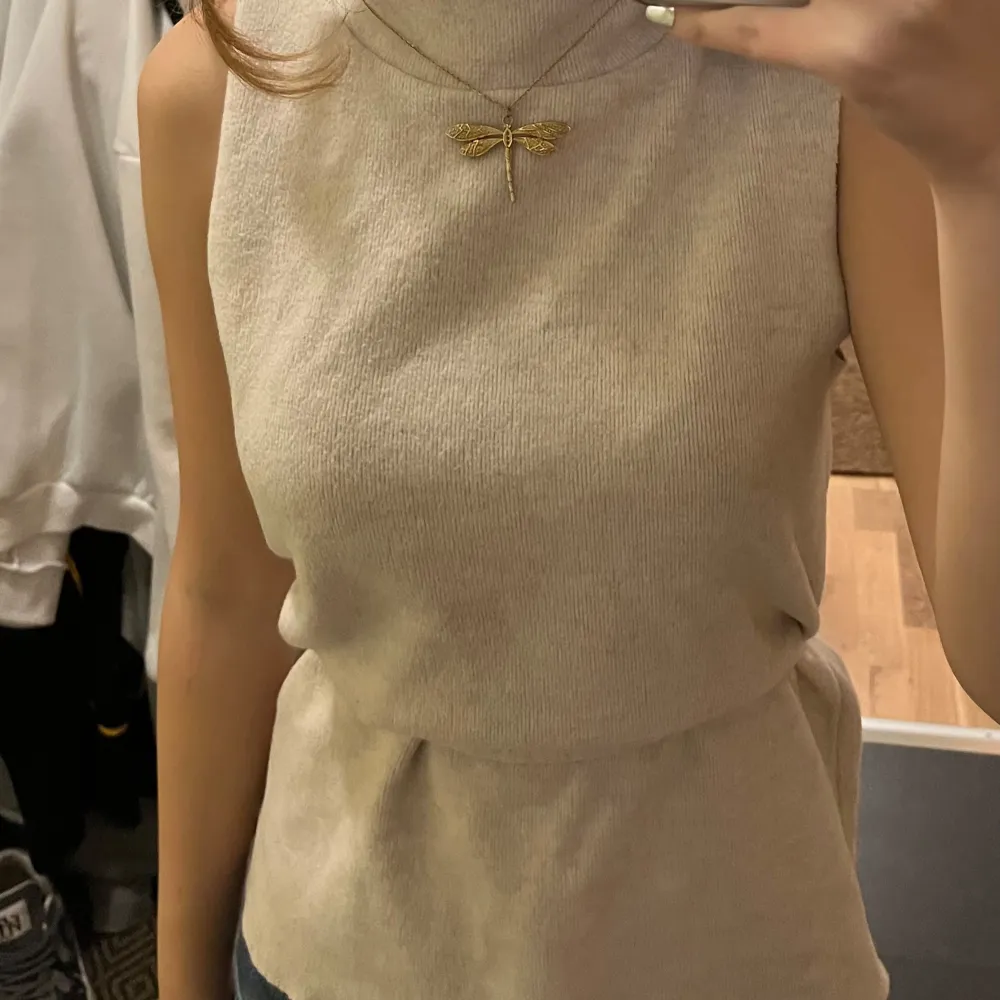 Säljer en superfin beige ärmlös topp i ribbat material från Zara . Den har en hög krage och ett snyggt knytband i midjan vilket gör att du kan använda den lite hur du vill. Jag visar två exempel i bilderna. . Toppar.