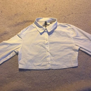 Vit croppad skjorta från H&M - Säljer en vit croppad skjorta från H&M Divided i storlek XXS. 