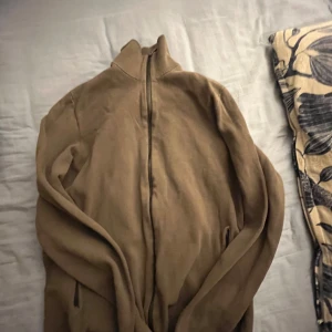 Brun tröja från Massimo Dutti - Säljer en snygg brun tröja från Massimo Dutti. Den är i ett mjukt material och har en dragkedja framtill. Perfekt för höst och vinter, och passar både till vardags och lite finare tillfällen. Tröjan har en normal passform och är i mycket bra skick.
