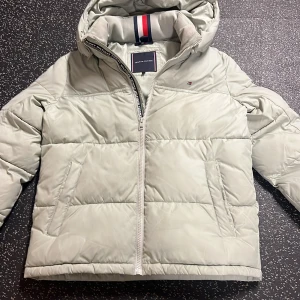 Tommy Hilfiger jacka - Hej säljer denna feta Tommy Hilfigier jackan som jag använt någon vinter men nu är förliste och ska säljas. Nypriset ligger runt 1800. Väldigt bekväm och skön jacka. Skulle säga att färgen är grön/vit. Ljusgrön men väldigt ljus. Pris kan diskuteras. 