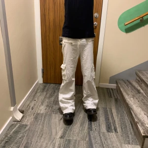 Vita cargobyxor med dragkedjor - Säljer ett par vita cargobyxor från Hitfire i herrstorlek 30. Byxorna har en loose passform och är utrustade med flera praktiska dragkedjor. Perfekta för en avslappnad stil eller vardagsäventyr. De är i bra skick och redo för nya äventyr! jag älskar ai beskrivningen, PRIS KAN DISKUTERAS 😜😜😜😜