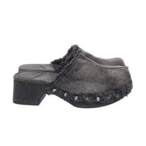 Svarta klackskor i jeansmaterial - Säljer ett par unika svarta klackskor i jeansmaterial med fransiga kanter och nitar längs sulan. Perfekta för en cool och avslappnad stil. De har en bekväm klack och är i bra skick. Passar perfekt till både vardag och fest. As coola! 