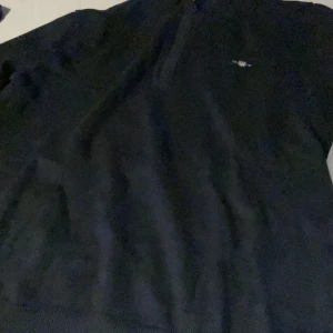 Svart tröja med dragkedja från GANT - Säljer en stilren svart tröja från GANT i mycket bra skick. Den har en dragkedja framtill och en liten logga på bröstet. Perfekt för både vardag och lite finare tillfällen. Passar bra till höst och vår! Ordinare pris 800kr