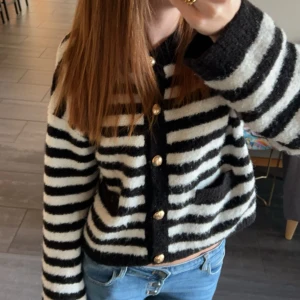 Randig kofta med guldknappar - Superfin randig kofta i svart och vit med snygga guldknappar. Den är perfekt för både vardag och fest. Koftan har långa ärmar och två praktiska fickor fram. Den är både mysig och stilren, perfekt för höst och vinter! Köpt på Gina Tricot för 600kr, använd ett fåtal gånger skulle tippa på 3-4. Bara att skriva om ni har frågor