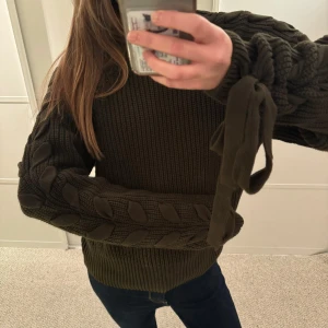Mörkgrön stickad tröja men snörning på ärmarna - Unik stickad tröja med snörning och knytning med rosett på ärmarna i mycket bra skick!!💕 köp gärna genom köp nu💞