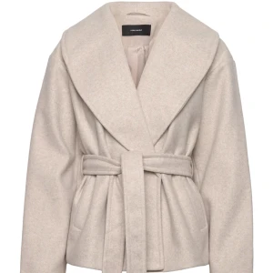 Beige kappa från Vero Moda - Snygg beige kappa från Vero Moda med ett brett bälte i midjan och med stor krage. Köpt förra säsongen och säljer för att den tyvärr inte kommer till användning längre. Köpt för 799 men säljer den nu för 400. Skriv för egna bilder! 