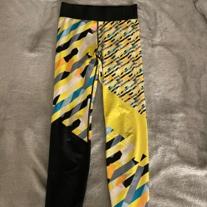 Färgglada mönstrade träningsthigts  - Snygga träningsbyxor med ett färgglatt och unikt mönster i gult, svart, blått och rosa. De har en elastisk midja för extra komfort och är perfekta för träning eller en färgstark vardagslook. 