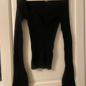 Svart ribbad tröja - Snygg svart ribbad tröja med lång ärm och en djup v-ringning.