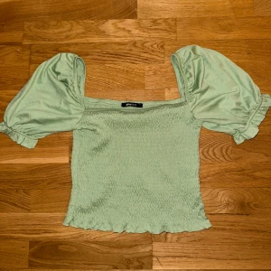 Grön topp från Gina Tricot - Säljer en söt grön topp från Gina Tricot med puffiga korta ärmar. Storlek L men skulle säga att det är mer som en M💚