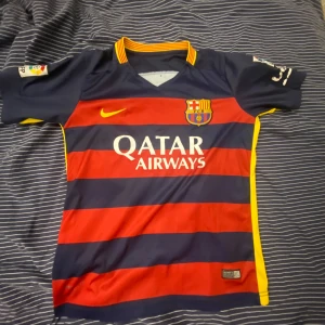 FC Barcelona fotbollströja från Nike - Säljer en autentisk FC Barcelona fotbollströja från Nike. Tröjan är randig i rött och blått med gula detaljer och korta ärmar. Den har klubbens emblem och sponsorloggor på framsidan samt UNICEF-logga på baksidan. Perfekt för alla Barça-fans! 🏆