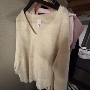 Beige v-ringad tröja från H&M - Säljer en stilren beige tröja från H&M med v-ringning. Tröjan har långa ärmar och en avslappnad passform, perfekt för en mysig dag. Passar bra till både jeans och kjol.