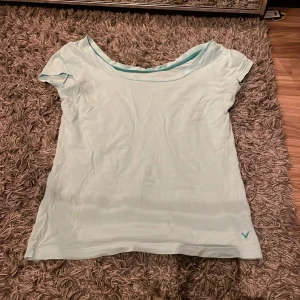 Ljusblå t-shirt från American Eagle - Säljer en ljusblå t-shirt från American Eagle. Den har en enkel design med korta ärmar och rund halsringning❤️