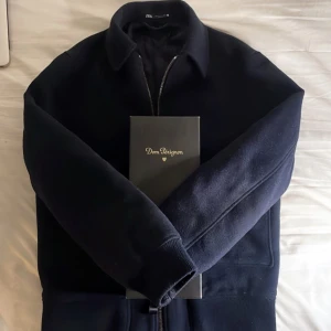 Mörkblå jacka från Zara - Snygg mörkblå jacka från Zara med dragkedja och krage. Jackan har långa ärmar och ribbade muddar vid ärmslut och nederkant. Perfekt för en stilen överdel, 