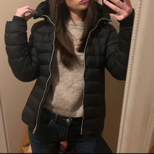 Svart dunjacka med dragkedja - Säljer en svart dunjacka från vinson polo club. Det är en dammodell med dragkedja och huva. Jackan har en ficka med dragkedja på ärmen och är perfekt för kyligare väder då den håller värme bra. I bra skick 💕💕