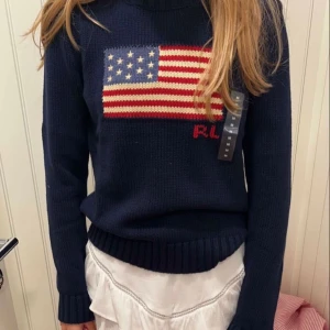 Mörkblå stickad tröja med amerikansk flagga - Säljer en snygg mörkblå stickad tröja från Ralph Lauren. Säljer för att jag inte får den till användning. Använt cirka 2 gånger, som ny. Köpt för 4995. Bilen är lånad