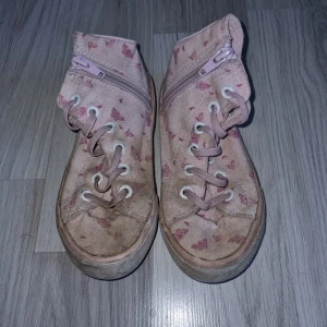 Rosa sneakers med fjärilsmönster - Säljer ett par rosa sneakers med sött fjärilsmönster. Skorna har både resår  och dragkedja på sidan för enkel på- och avtagning. Perfekta för en avslappnad stil.
