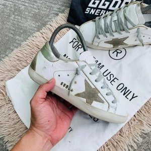 Vita sneakers från Golden Goose - Snygga vita sneakers från Golden Goose med en stjärndetalj i guld på sidan. Skorna har en klassisk design med snörning och en robust sula. Perfekta för en stilren look.