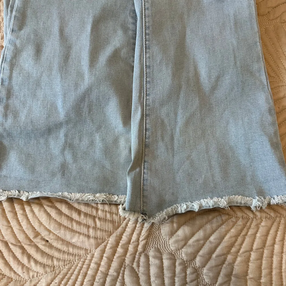 Snygga ljusblå jeans med fransar vid bensluten. De har en klassisk femficksdesign och en avslappnad passform. Perfekta för en casual look.. Farkut & Housut.