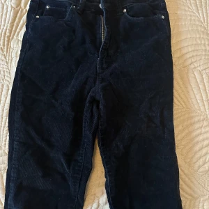 Mörkblå  manchesterbyxor - Snygga svarta manchesterbyxor med dragkedja och knappar. Perfekta för en stilren look med en klassisk touch. Byxorna har en rak passform och är tillverkade i mjukt manchestertyg.