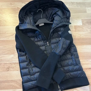 Moncler cardigan - Moncler cardigan. En perfekt jacka för våren den sitter riktigt bra har en skön och stilren luva. Jackan är i 10/10 skick den är för liten för mig därför säljer jag den. Jackan är riktigt varm och lätt att matcha. Jag rekommenderar verkligen den till alla där ute passa på nu innan våren.