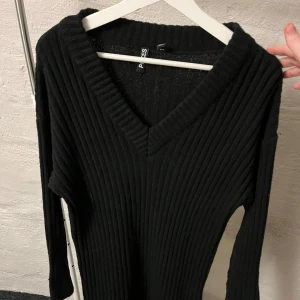 Svart stickad klänning  - Denna svarta mid klänning är otroligt mjuk och skön, har en fin v-ringning, är lång i ärmarna och går till knänen. 