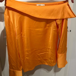 Orange topp NA-KD X Andrea Hedenstedt - Orange topp, snedskuren vid huvud-axlar. Fint armslut med bred kant och knapp. Strl 36/S