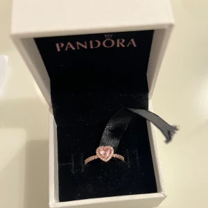 Pandora Ring Rosa - Elegant ring från Pandora i rosa färgen med en hjärtformad sten i mitten. Ringen är helt ny och oanvänd. Säljer eftersom fick den som present och den passar inte mig. 