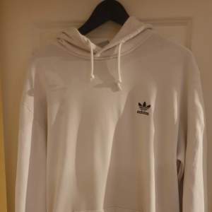 Säljer en snygg vit hoodie från Adidas i storlek L. Den är i bra skick och har en klassisk design med Adidas-loggan på bröstet. Perfekt för både vardag och träning. Den har en stor ficka fram och en bekväm huva med dragsko. Primegreen-material för en hållbar touch.