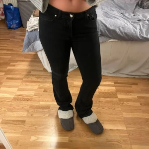Svarta midwaist jeans från gina tricot  - Säljer ett par svarta jeans från gina tricot i storlek 38. De har en klassisk design med fem fickor och knappgylf. Jeansen är i bra skick men är lite slitna längst ner då de är för långa för mig! 