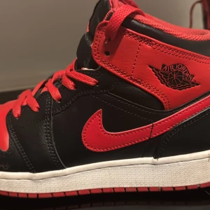Nike Air Jordans i svart och rött - Säljer ett par snygga Nike Air Jordans i svart och rött. Skorna har en klassisk design med röd snörning och den ikoniska Air Jordan-loggan på sidan. Perfekta för både vardag och fest! 🏀