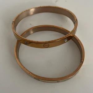 Guldarmband med stenar - Säljer två stilrena guldarmband med gnistrande stenar. De har en elegant och tidlös design med små skruvdetaljer. Perfekta för både vardag och fest! ✨