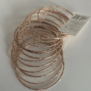 Glittriga armband i roséguld - Säljer ett set med flera glittriga armband i roséguld, 15 st. De är tunna och eleganta, perfekta för att ge lite extra bling till din outfit. Passar både till vardags och festliga tillfällen. Armbanden är i nytt skick och kommer med etikett. Perfekt accessoar för att lyfta vilken look som helst! ✨