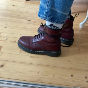 Vinröda boots från Dr. Martens - Säljer ett par klassiska vinröda Dr. Martens boots i skinn. Skorna är i mycket bra skick. Men har en missfärgning (se bild 2)  säljer pågrund av att dem inte passar min fot (samma bilder som dem jag köpte dem av) 