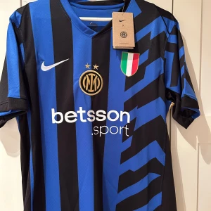 Inter tröja Nike  - Säljer en snygg blå och svart randig fotbollströja från Nike. Tröjan har korta ärmar och ett coolt mönster med klubbmärke och sponsorlogga på framsidan. Perfekt för fotbollsfans som vill visa sitt stöd. Tröjan är i nytt skick och redo för match eller vardag. Har inte använt den helt ny pris för att diskutera 