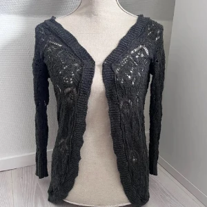 Cardigan - Mörkgrå cardigan. Korta ärmar. Lite nopprig inget som syns mycket.