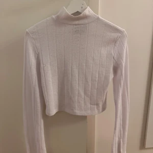 Vit ribbad polotröja från AFJ - Säljer en superfin vit ribbad polotröja från AFJ i storlek S. Den är lite genomskinlig och har långa ärmar med slits. 