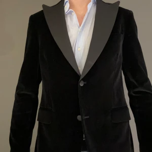 Svart sammetkavaj från Oscar Jacobson - Säljer en elegant svart kavaj i sammet från Oscar Jacobson. Perfekt för festliga tillfällen med sin stilrena design och mjuka material. Kavajen har en klassisk passform med två knappar och spetsiga slag. Passar utmärkt till fest eller bal tillfällen. Tveka inte på att höra av dig vid ytterligare frågor samt fler/bättre bilder!☺️ 
