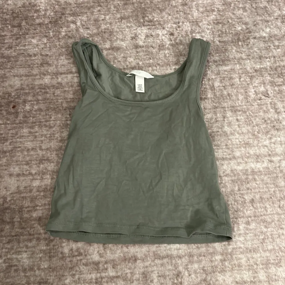 Säljer en stilren grön linnetopp från H&M i storlek XS. Toppen är ärmlös och perfekt för sommardagar. Den har en enkel design med rund halsringning och är gjord i ett mjukt bomullsmaterial. Perfekt att matcha med jeans eller shorts för en avslappnad look. Nästan aldig andvänd. Toppar.