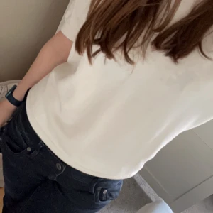 Vit kortärmad topp - Säljer en stilren vit topp med korta puffärmar. Perfekt för både vardag och festliga tillfällen. Toppen har en rund halsringning och är gjord i ett mjukt material som känns skönt mot huden. Har en lite fläck men syns inte 