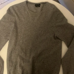 Grå kashmirtröja från Massimo Dutti - Säljer en supermjuk och lyxig grå kashmirtröja från Massimo Dutti. Perfekt för kyliga dagar med sin stilrena design och bekväma passform. Tröjan har långa ärmar och en klassisk rund halsringning. Ett måste för garderoben! 🧶Tyvärr har tröjan haft ett hål som lagats men kolla bild 3 för att se, ingen man tänker på när man har den på sig.