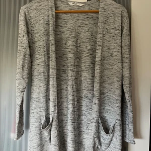 Grå kofta från H&M - Mysig grå kofta från H&M i mjukt material. Perfekt för lager-på-lager under höst och vår. Den har långa ärmar och praktiska fickor framtill. Enkel och stilren design som passar till det mesta. Perfekt för en avslappnad look!