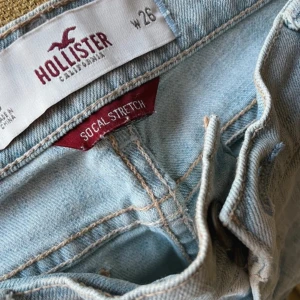 Ljusa jeansshort från Hollister - Säljer ett par ljusa jeansshorts från Hollister i storlek W26. De har en snygg slitning och är perfekta för sommaren. Shortsen är lågmidjade och har en avslappnad stil med råa kanter. 🌞säljer dessa för dem sitter lite för stort på mig.