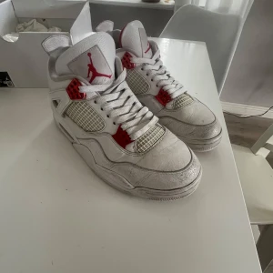 Jordan 4 retro metallic red - Säljer ett par klassiska vita Nike Air Jordans med röda detaljer. Skorna har snörning och är i bra skick, perfekta för både vardag och fest. De kommer i originalkartong.