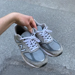 New balance 990v5 grå sneakers - Säljer ett par grå sneakers från New Balance i bra men använt skick. De har en klassisk design med snörning och är perfekta för vardagsbruk. Skorna är tillverkade i suede läder och meshstruktur som tillåter skorna att andas. De har en bekväm passform och fotsula. En riktig favorit. Passar mig som brukar ha 44 i skostorlek.