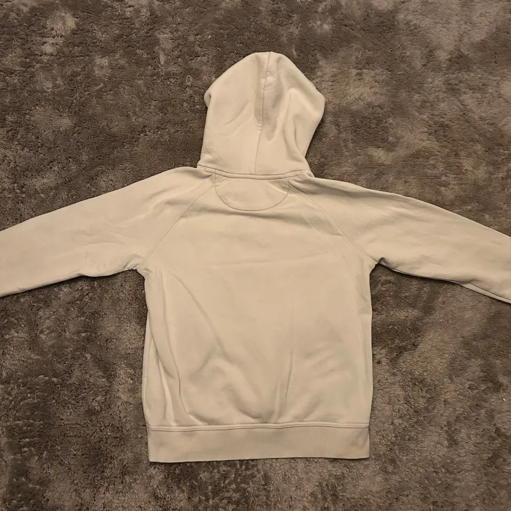 Säljer en stilren vit hoodie från GANT i storlek 158-164cm. Hoodien är i bra skick och har en bekväm passform med känguruficka framtill. Hoodien har väldigt få osynliga defekter, ända fläcken man kan se är den som är på bilden.. Tröjor & Koftor.