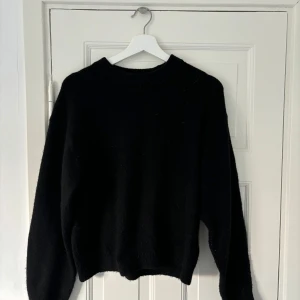 Stickad tröja - Säljer en klassisk svart stickad tröja från H&M som är perfekt för kyliga dagar. Den har en enkel design med långa ärmar och en bekväm passform. Perfekt att matcha med jeans eller kjol för en stilren look.