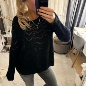Svart stickad tröja - Säljer en supermysig svart stickad tröja med ett snyggt hålmönster. Perfekt för höst och vinter! Tröjan har långa ärmar och en lös passform som gör den extra bekväm. 🖤