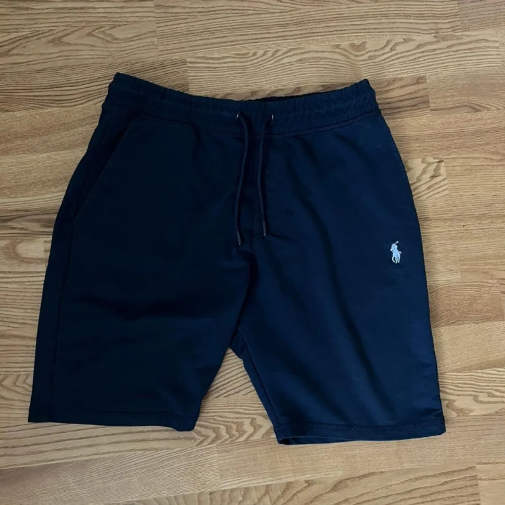 Snygga mörkblåa bomullshorts från Polo Ralph Lauren i ett material. Normal passform, soft att ha hemma men även ute på sommaren. Clean som f*n, typ oanvända. Shortsen har en diskret logga på ena benet och snörning i midjan. Säljes för att de inte passar mig. Nypris 1589. Shorts.